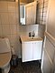 Kompaktes Badezimmer in Nordland, Norwegen: Fliesenwände, weißes Waschbecken mit Spiegel, WC und eleganter Holztür. Perfekt für Angelurlauber, die Komfort in rustikaler Umgebung suchen.
