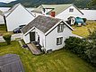 Nord-Norwegen: Weißes Holzhaus, idyllisch am Fjord gelegen. Umgeben von grünen Wiesen und Bergen, bietet es perfekten Ausgangspunkt für Angelabenteuer und Naturerlebnisse in beeindruckender Umgebung. Perfekt für Erholung und Entdeckung in unberührter Natur.