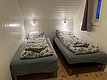 Gemütliches Zimmer in Nord-Norwegen mit zwei Einzelbetten, Holzboden und weicher Beleuchtung. Ideale Unterkunft für Angelurlauber, die nach einem erlebnisreichen Tag entspannen möchten. Perfekt für Komfort und Erholung in der Natur.