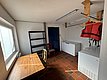 Ein praktischer Raum in Hitra, Norwegen, mit Tisch, Stühlen, Gefriertruhen und einem Regal. Ideal für Vorbereitung nach erfolgreichem Angelurlaub. Schwimmweste und Holzkleiderbügel für Sicherheit und Komfort.