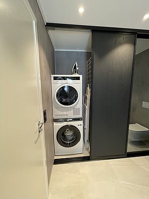 Moderne Waschküche in Hitra, Norwegen: Waschmaschine und Trockner in schlichtem, stilvollem Raum. Perfekt für komfortable Angelurlaube mit praktischer Ausstattung. Ideal für Outdoor-Abenteuer und stressfreies Reisen.