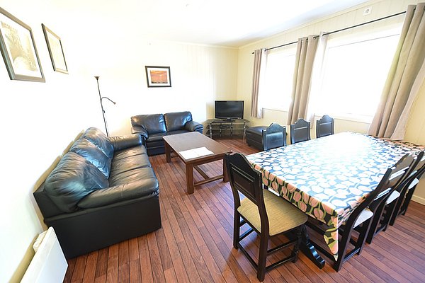 Gemütliches Wohnzimmer in Hitra, Norwegen, mit Ledersofas, großem Esstisch und TV. Ideal für Erholung nach einem abenteuerlichen Angelurlaub in den malerischen norwegischen Fjorden. Perfekte Unterkunft für entspannte Abende nach erfolgreichen Angelausflügen.