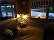 Gemütliches Wohnzimmer mit Rattan-Stühlen, indirekter Beleuchtung und Blick auf einen ruhigen See durch das Fenster.