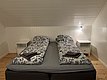 Gemütliches Schlafzimmer in Nord-Norwegen: Helles, schlichtes Design mit zwei Einzelbetten, weißer Holzverkleidung und Nachttischen. Perfekt für erholsame Nächte nach abenteuerlichen Angelausflügen. Ideal für einen erholsamen Angelurlaub im hohen Norden.