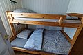 Gemütliches Zimmer mit Etagenbett aus Holz in Hitra, Norwegen. Ideal für Angelurlauber. Helle Wände, bequeme Betten. Perfekter Rückzugsort nach einem langen Angeltag. Entspannung und Komfort für Abenteurer.