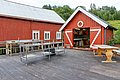 Rote Holzhütten am Wasser in Hitra, Norwegen. Perfekte Location für Angelreisen mit Fischreinigungstisch und gemütlicher Sitzgelegenheit, umgeben von üppigem Grün. Ideal für Abenteuer und Entspannung in der Natur.