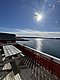 Sonnige Terrasse mit Blick auf das glitzernde Meer bei Hitra, Norwegen. Rote Holzhäuser strahlen skandinavisches Flair aus. Ideal für Angelurlaub und Naturliebhaber. Perfekte Kulisse für Erholung und Abenteuer.