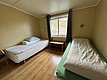 Gemütliches Zimmer in Hitra, Norwegen, mit zwei Einzelbetten, Holzfußboden und Fensterblick. Perfekte Unterkunft für Angelurlauber, die Ruhe und Komfort schätzen. Hell und einladend gestaltet. Ideal für erholsame Nächte nach erfolgreichen Angeltagen.