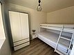 Helles Schlafzimmer in Nord-Norwegen mit Etagenbett, Kleiderschrank und Nachttisch. Ideal für Angelurlaub, gemütlich und funktional eingerichtet, perfekt zum Ausruhen nach einem erfolgreichen Fangtag.