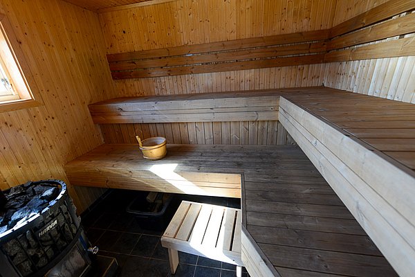 Gemütliche Holzsauna in Nord-Norwegen mit robusten Holzbänken und traditionellem Saunaofen. Entspannende Atmosphäre für Angler nach einem kühlen Tag am Meer. Perfekt zur Erholung und Regeneration. Ideal für Angelurlaub und Entspannung in Norwegen.