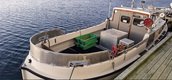 Ein kleines Fischerboot liegt an einem Holzsteg, umgeben von ruhigem Wasser, mit leeren Kisten und Ausrüstung an Bord. Ein kleines Fischerboot liegt an einem Holzsteg, umgeben von ruhigem Wasser, mit leeren Kisten und Ausrüstung an Bord.