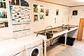 Küchenbereich in Nord-Norwegen mit Fischvorbereitungsstation, Spülbecken und Waschmaschine. Wanddekorationen zeigen Fischarten und Angelbilder. Ideal für Angler, die ihre Fänge direkt vor Ort verarbeiten möchten.
