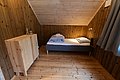 Gemütliches Schlafzimmer aus Holz in Nord-Norwegen, mit Einzelbett und minimalistischem Schrank, bietet eine warme und einladende Atmosphäre für naturnahe Erholung. Ideal für Angler und Reisende in skandinavischer Umgebung.