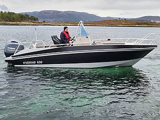 Motorboot auf klarer See in Nord-Norwegen, umgeben von beeindruckender Bergkulisse. Perfekte Bedingungen für einen Angelurlaub mit großem Fangpotenzial. Ideal für Abenteurer und Naturfreunde. Petri Heil – sorglos angeln!