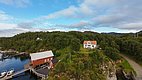 Küste von Hitra, Norwegen: Rotes Bootshaus am Wasser, umgeben von dichter grüner Natur. Perfekter Ort für Angelreisen und Erholung in skandinavischer Idylle. Abenteuer und Entspannung in beeindruckender Landschaft.