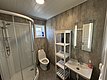 Modernes Badezimmer in Hitra, Norwegen: Duschecke, Toilette, Waschbecken und Regal, helle Holzdecken und graue Wände. Perfekt nach einem erholsamen Angeltag. Ideal für Angelreisen.