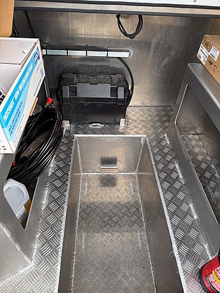 Angelboot-Stauraum aus Aluminium in Südwest-Norwegen: Der gut organisierte Lagerbereich zeigt robuste Bauweise mit rutschfester Oberfläche, ideal für sicheres Verstauen von Ausrüstung und Batterien bei Angelabenteuern in Fjorden oder auf dem offenen Meer.