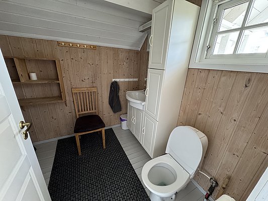 Gemütliches Badezimmer in Hitra, Norwegen mit Holzverkleidung, weißen Schränken und natürlichem Licht. Ideal für Angler auf Angelreise, die Komfort und skandinavisches Flair nach einem erfolgreichen Angeltag suchen.