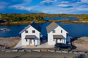 Zwei weiße Ferienhäuser direkt am Wasser in der malerischen Landschaft von Hitra, Norwegen. Traumhafter Angelurlaub mit spektakulärer Naturkulisse und exzellenter Lage für Meeresangeln. Perfekt für Abenteuer und Entspannung.