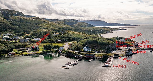 Luftaufnahme von Norwegens Hitra: Küstenlandschaft mit Hügeln, Bootsanleger und Filetierhaus. Perfektes Angelreiseziel mit vielfältigen Fischarten wie Köhler, Hering und Heilbutt. Ideal für Angelurlaub in idyllischer Naturkulisse.