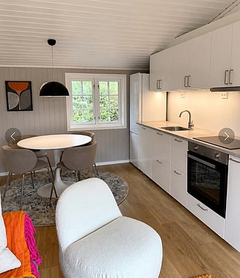 Gemütliche Unterkunft in Hitra, Norwegen: Moderne Küche, runder Esstisch, helle Holzböden, minimalistische Einrichtung. Ideal für Angelurlaub in skandinavischer Natur. Perfekt für erholsame Momente nach erfolgreichen Angelausflügen.