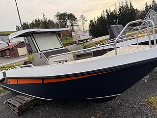 Ein modernes Aluminiumboot von AluVenture steht auf einem Grundstück in Südwest-Norwegen, umgeben von Bäumen und Gebäuden. Perfekt für Angelreisen und Bootstouren in skandinavischen Gewässern.