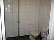 Helles Badezimmer in Nord-Norwegen mit Dusche, WC und Waschbecken. Moderne, schlichte Fliesen in Weiß gestalten eine funktionale Atmosphäre. Ideal für einen komfortablen Aufenthalt während eines Angelurlaubs.