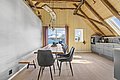 Gemütlicher Essbereich in Südwest-Norwegen mit Holzwänden, modernen Möbeln und großem Fenster mit Blick auf schneebedeckte Berge. Perfekt für Angelreisende, die Entspannung und beeindruckende Landschaften genießen möchten. Skandinavisches Design trifft Naturschönheit.