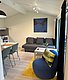 Gemütliches Ferienhaus in Hitra, Norwegen: Modern eingerichtetes Wohnzimmer mit Schlafsofa, blauem Sessel, Esstisch und Kunstwerk. Perfekt für entspannte Angelurlaube mit viel Komfort und skandinavischem Flair. Ideal für erholsame Tage nach erfolgreichem Fischen.