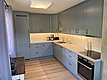 Moderne Küche in Nord-Norwegen, mit grauen Schränken, Elektrogeräten und Holzarbeitsplatte. Ideal für Selbstversorger während des Angelurlaubs. Warme Beleuchtung schafft eine einladende Atmosphäre. Perfekt für entspannte Abende nach einem erfolgreichen Angeltag.