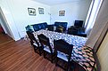 Gemütliches Wohnzimmer in Hitra, Norwegen: Holzboden, langer Esstisch mit gemusterter Tischdecke, Ledersofas, kleiner Fernseher und dekorative Wandbilder. Perfekt für entspannte Abende nach einem erfolgreichen Angeltag in der Umgebung.