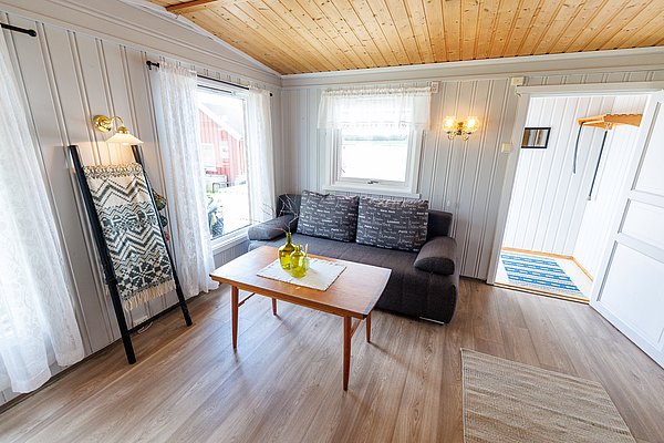 Gemütliches skandinavisches Wohnzimmer in Hitra, Norwegen. Helle Holzelemente, moderne Dekoration und viel Tageslicht schaffen eine einladende Atmosphäre. Ideal für entspannte Angelurlaube.