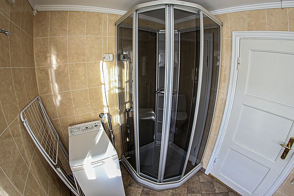 Kompaktes norwegisches Badezimmer mit moderner Duschkabine, Waschmaschine und Hellbeige-Fliesen. Ideal für Angelurlauber in Nord-Norwegen, die Komfort und Funktionalität nach einem erfolgreichen Angeltag suchen. Optimale Ausstattung für Erholung und Entspannung.