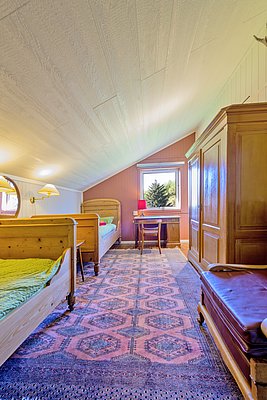 Gemütliches Zimmer in Nordland, Norwegen, mit Holzbetten, Teppich und Blick auf Bäume durch ein Fenster. Ideal für erholsame Angelurlaubstage. Nachhaltige Einrichtung und entspannte Atmosphäre für Abenteuer und Erholung in der Natur.