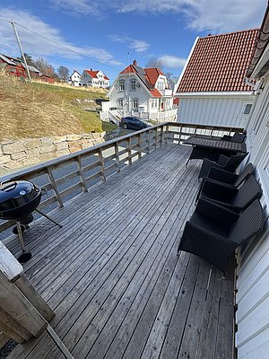 Gemütliche Terrasse mit Blick auf traditionelle weiße Holzhäuser und roten Dächern in Hitra, Norwegen. Ideal für Angelreisende, die Ruhe und skandinavische Architektur genießen. Perfekte Basis für Abenteuer und Meeresangeln.
