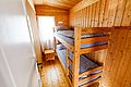 Gemütliches Holzschlafzimmer mit Etagenbett in einer Hütte in Hitra, Norwegen. Ideal für Angelurlaub. Helle Einrichtung, Fenster mit Vorhang, kleiner Holztisch. Perfekt für naturverbundene Erholung.