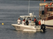 Motorboot mit mehreren Personen im Hafen von Sao Vicente, Kapverden. Blaues Meer, angrenzendes größeres Boot. Maritime Szene ideal für Angelreisen und Erkundungstouren. Authentisches Küstenerlebnis auf Kap Verden.