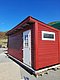 Rotes Holzhaus in Hitra, Norwegen, unter klarem blauem Himmel. Traditionelle skandinavische Architektur, idealer Ausgangspunkt für Angelurlaube. Erleben Sie nachhaltigen Tourismus in natürlicher Schönheit. Perfekt für Naturliebhaber und Abenteuerlustige.