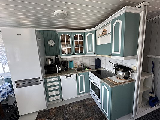 Gemütliche Küche im traditionellen Stil auf Hitra, Norwegen. Helle, grüne Schränke, moderne Elektrogeräte und praktische Einrichtung. Perfekt für Angelurlaub, um frisch gefangenen Fisch zuzubereiten. Optimaler Komfort nach einem erfolgreichen Angeltag.