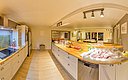 Gemütliche, moderne Küche in einem norwegischen Ferienhaus in Nordland. Holzböden, helle Schränke und gut ausgestattete Arbeitsflächen. Ideal für Angelreisende, um frisch gefangenen Fisch zuzubereiten. Perfekter Ort für Erholung und Genuss im Urlaub.