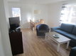 Helles Wohnzimmer in Hälsingland, Schweden. Moderne Einrichtung mit blauem Sofa, Sessel, Couchtisch und Esstisch. Große Fenster sorgen für viel Tageslicht. Ideal für erholsamen Angelurlaub.