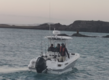 Angeltour in São Vicente, Kapverden: Ein Boot mit Anglern fährt bei ruhigem Meer und felsiger Küstenlinie in die Dämmerung. Ideal für einen unvergesslichen Angelurlaub.
