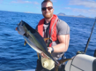 Ein Angler hält stolz einen großen Fisch auf einem Boot vor der Küste von Sao-Vicente, Kapverden. Die atemberaubende Meereslandschaft lädt zu einem unvergesslichen Angelurlaub ein.