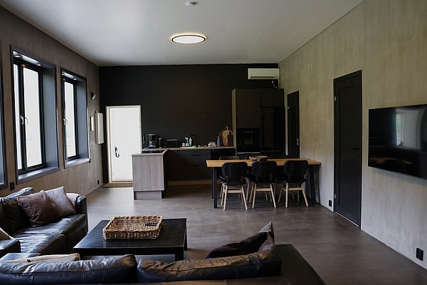 Modern eingerichtetes Wohnzimmer in Nordland, Norwegen. Die stilvolle Lounge verfügt über Ledersofas, einen Esstisch und eine offene Küche. Ideal für Angelreisende, die Komfort nach einem erfolgreichen Tag am Wasser suchen.