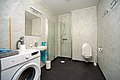 Modernes Badezimmer in Hitra, Norwegen, mit Waschmaschine, Dusche und WC. Helle Fliesen sorgen für ein einladendes Ambiente. Ideal für Angelurlauber, um Komfort und Funktionalität nach einem erfolgreichen Tag am Wasser zu genießen.
