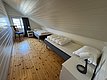 Gemütliches Schlafzimmer mit zwei Einzelbetten, hellem Holzboden und Dachschräge in norwegischer Ferienunterkunft. Perfekt für erholsame Nächte auf der Angelreise in Hitra, Norwegen. Ruhige, einladende Atmosphäre mit Fensterblick.