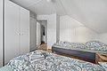 Gemütliches Schlafzimmer in Nord-Norwegen: Helle Holzwände, zwei Einzelbetten mit gemusterten Bezügen, Kleiderschrank, Holzfußboden. Ideal für Angelreisen, um nach erfolgreichen Tagen in der nordischen Natur zu entspannen.