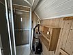 Gemütliches Badezimmer in Hitra, Norwegen: Holzwände, Dusche mit transparenter Tür, Stauraumregal, Staubsauger. Perfekt für Angelurlauber, die Komfort in skandinavischer Umgebung suchen. Nahe am Wasser, ideal für entspannte Erholung nach abenteuerlichen Angelausflügen.