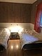 Gemütliches Schlafzimmer in Hitra, Norwegen: Zwei Einzelbetten, Holzwand, Parkettboden und Nachtlichter bieten eine entspannte Atmosphäre nach einem ereignisreichen Angeltag. Ideal für einen erholsamen Angelurlaub.