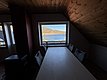 Gemütlicher Raum in Hitra, Norwegen, mit Holzdecke und Panoramafenster. Blick auf ruhigen Fjord und bewaldete Hügel. Ideal für Angler, die Entspannung und atemberaubende Natur erleben möchten. Perfekte Mischung aus Komfort und Abenteuer.